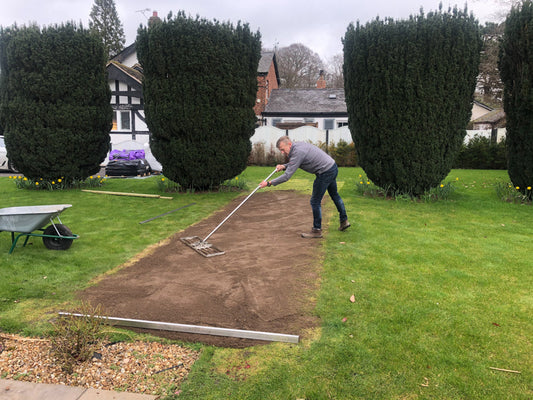 A man levelling a lawn with a lute